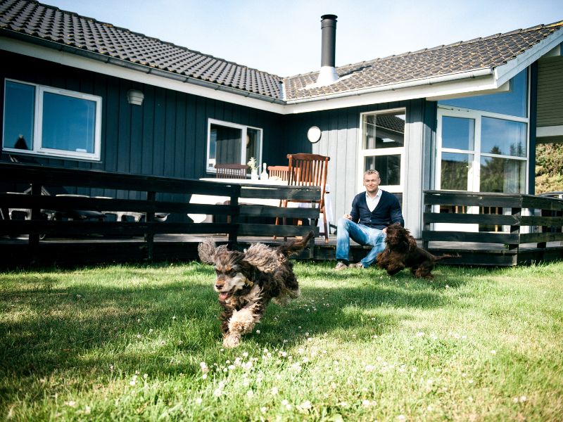 Urlaub mit Hund Dänemark - Ein Mann lässt zwei Hunde frei laufen im Garten