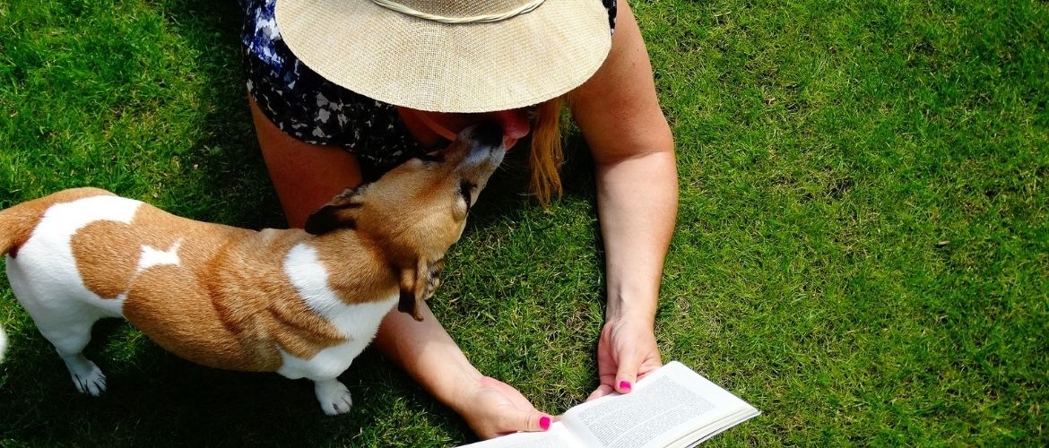 Frau liest ein Buch mit Hund