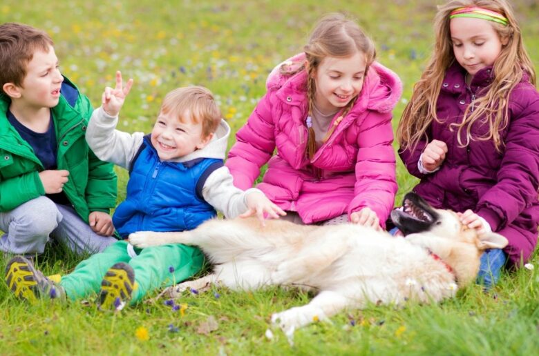 Kinderfreundliche Hunderassen: Kinder spielen mit einem Hund auf dem Rasen