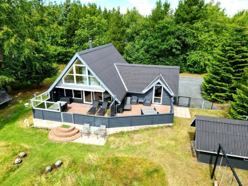 Kobmand Hansens Ferienpark - Ein Ferienhaus mit eingezausten Terrasse vor einem Wald